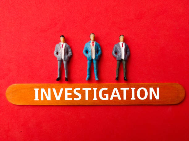 istock Miniature people with the word INVESTIGATION  on a red background 2137023509