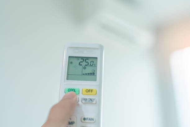 istock hand operating remote controller for adjust Air conditioner inside the room of office or house 2137045811
