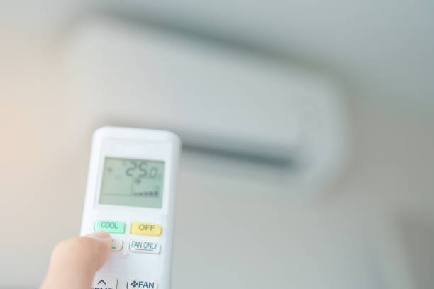 istock hand operating remote controller for adjust Air conditioner inside the room of office or house 2137046320