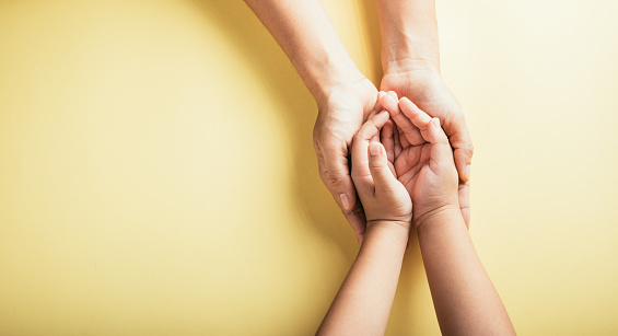 Studio shot, Close-up top view of family hands stacked isolated background. Parents and child hold empty space together signifying support and love on Family and Parents Day.