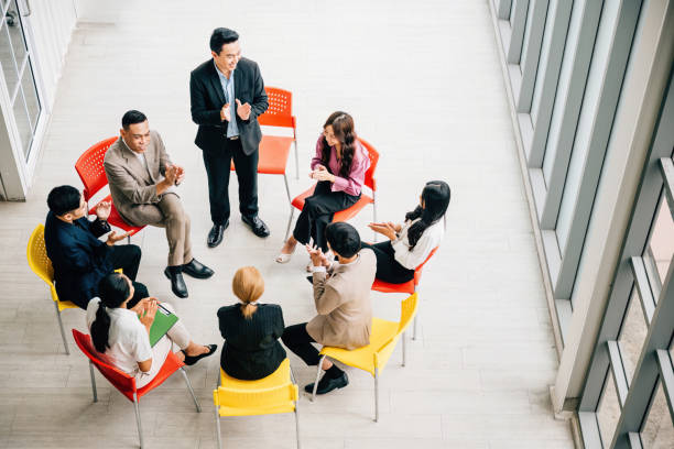 istock Top view captures a diverse group in a busy office, collaborating and engaged in discussions. A businessman and businesswoman sit at a conference, allowing for your business meeting concept. 2137057355