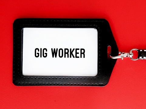 ID card holder on red background with text GIG WORKER - someone who works in gig economy as independent contractor or freelancer, self-employed rather than employees