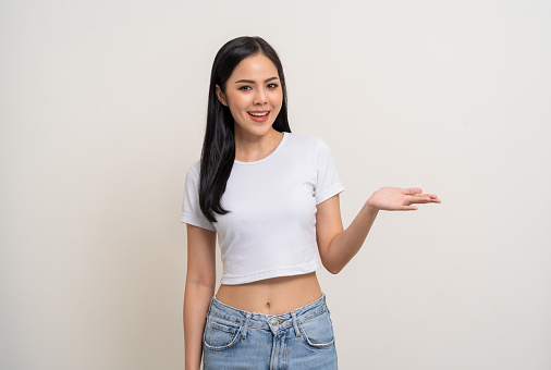 Beautiful smiling happy young asian woman in white shirt. Charming female lady open hands palm up holding something on isolated white background. Asian woman cute Pretty people looking blank space.