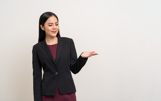 Attractive Young asian business woman smiling to camera standing pose on isolated white background. Latin Female around 25 in black suit portrait shot in studio.