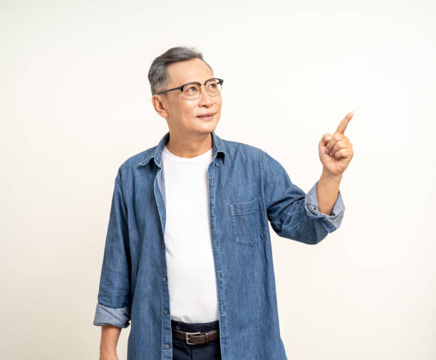 istock Handsome asian mature old man standing pointing finger to blank space isolated white background. Happy Portrait of cheerful smiling senior asian man looking at camera. Mature People and lifestyle 2137117173