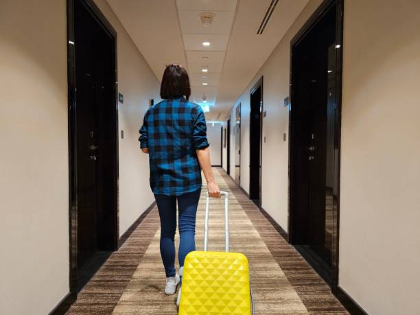 istock Woman Walking Down a Hallway With Yellow Suitcase 2137119274