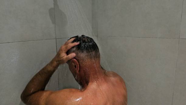 istock Man Standing in Shower With Head Under Water 2137125010