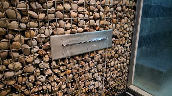 A shower with an unconventional design, featuring a wall adorned with a variety of rocks of different shapes and sizes