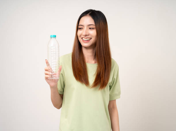 istock Young asian beautiful woman holding plastic of bottle assume Garbage sorting before throwing them into the bin. Activist environmental woman in green shirt with recycle and sustainability concept. 2137133688