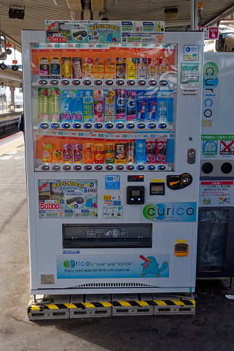 White vending machine at platform of Japanese railway station at metropolis of Tokyo on a sunny winter day. Photo taken February 7th, 2024, Tokyo, Japan.
