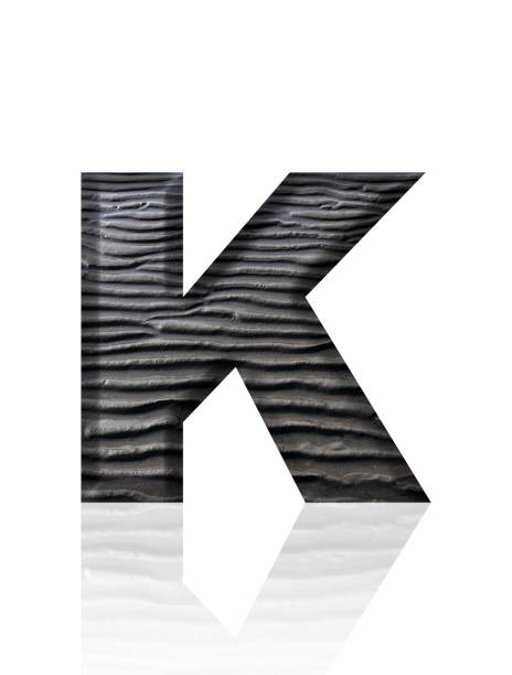 Close-up of three-dimensional mud flat pattern alphabet letter K on white background.
