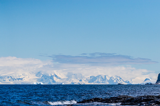 A tranquil Antarctic landscape, near Mikkelsen Harbour on Trinity Island, highlighting stark reflections, rugged mountains, and impressive icebergs