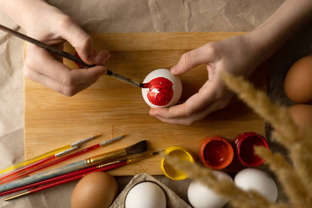 Preparation for Easter. A child paints an Easter egg with bright colors
