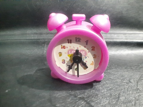 Pink toy table clock: cute, compact, whimsical, accurate, portable, charming, vibrant, stylish, functional.