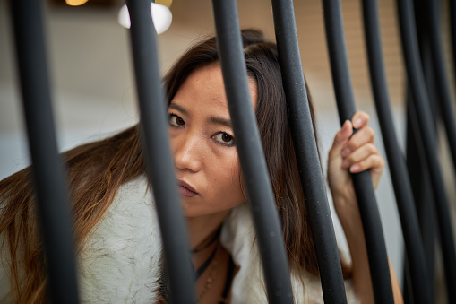 Japanese female showing attitude and questioning from behind a security screen stares at the camera, moody look with unique appearance.