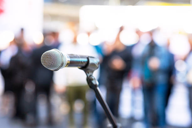 istock Microphone in focus against blurred audience. Public relations - PR concept. 2137312005