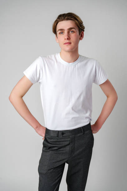 istock Young Man in White T-Shirt and Grey Trousers Posing Against a Plain Background 2137331868