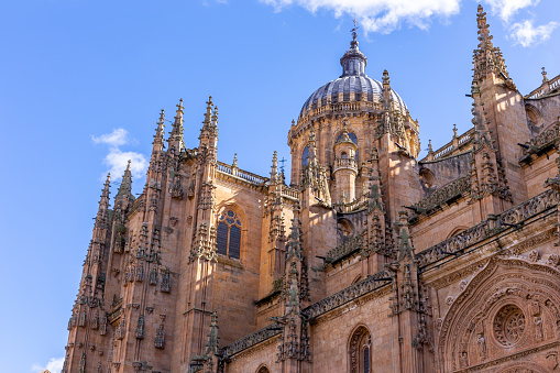 New Cathedral of Salamanca (Catedral Nueva) decorative facade with spires and dome, gothic and baroque architecture, against blue sky.