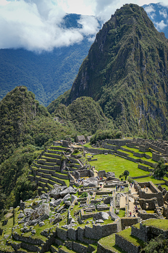 A portrait shot of Machu Picchu’s ancient ruins, with forested mountains in the background.