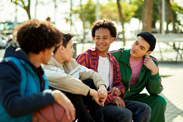 nyugodt csoport, amely a szabadban ül a napsütésben és beszélget - tizenéves fiúk témájú stock jellegű vizuális alkotások, jogdíjmentes fotók és képek