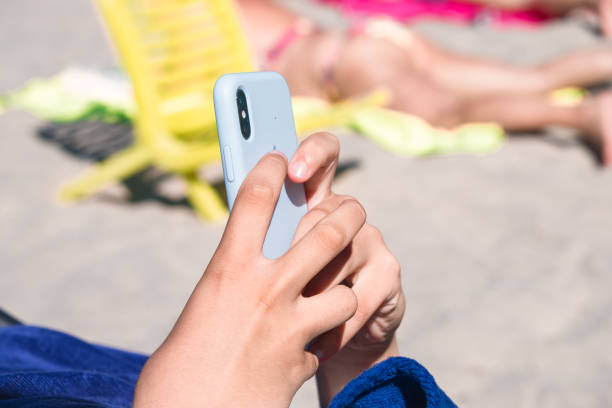 istock a teenager using her smartphone while sunbathing on the beach in summertime 2137422796
