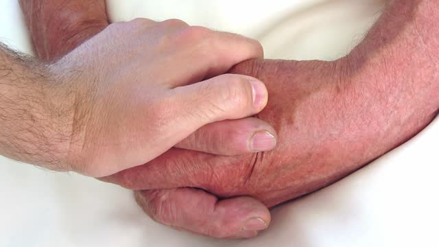 Man Holding Senior Man's Hands And Comforting Him