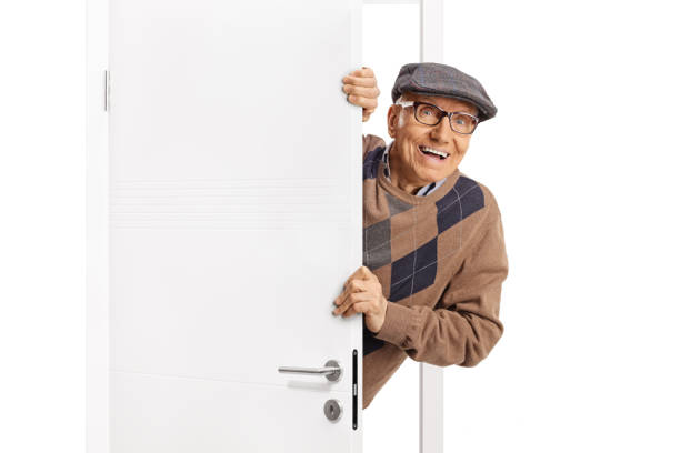 istock Elderly man smiling and peeking from behind a white door 2137453032