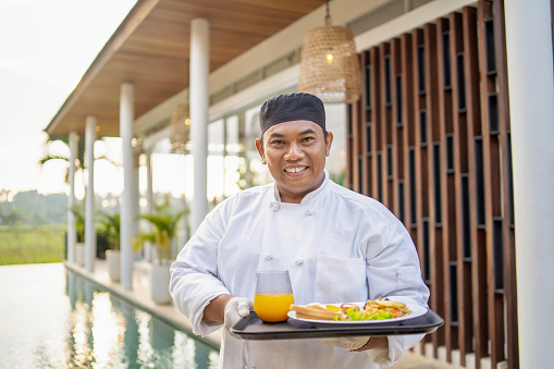 Portrait of dedicated chef looking at camera while serving meal outside of luxury villa