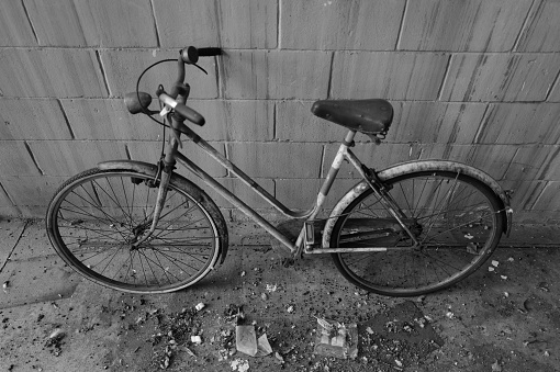 Old and rusty bicycle parked against a city wall