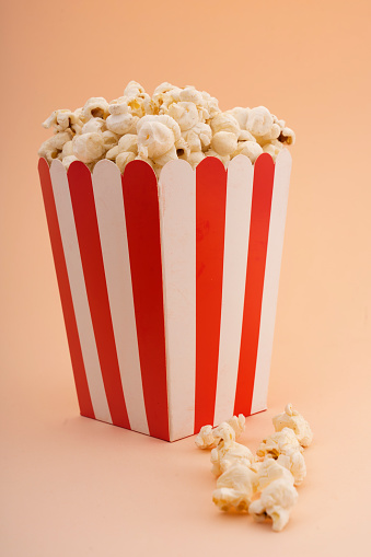 A striped popcorn bucket on a tan background.