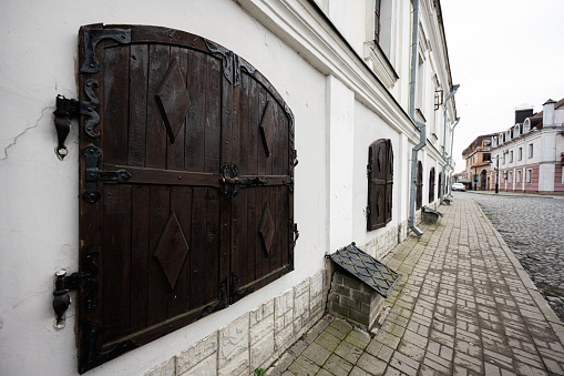 A quaint cobblestone street lined with historic buildings featuring large wooden shutters in a serene European town.