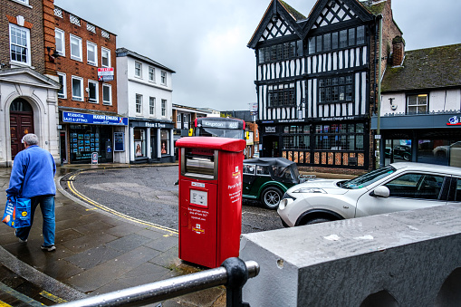 Leatherhead Surrey, UK, April 03 2024, Woman Carrying Shopping Walking Past A Royal Mail Parcel Post Box On A Wet Day