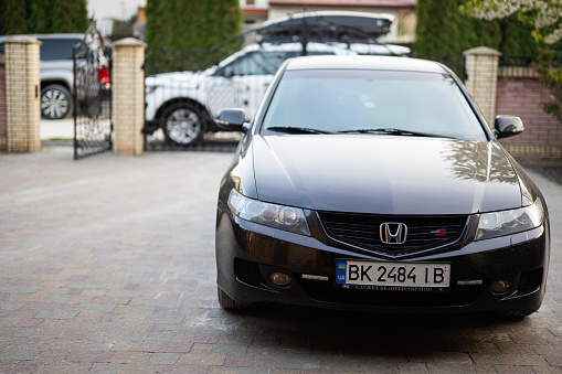 Ternopil, Ukraine- March, 2023: A black Honda Accord car parked in the driveway of a residential home, ready for a family outing or daily commute.