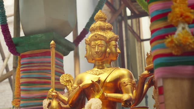 Closeup shot of golden statue sculpture of Brahma Phra Phrom 4 faced god in hindu and buddhism around colorful temple, hinduism religious atmosphere