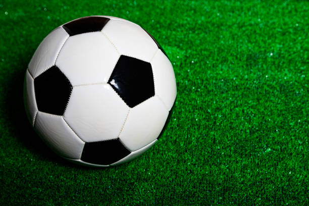 A classic black and white soccer ball over a green grass surface.
