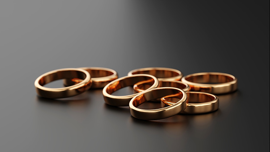 Several gold rings piled up on a black background. Designed with 3D rendering, macro focus.