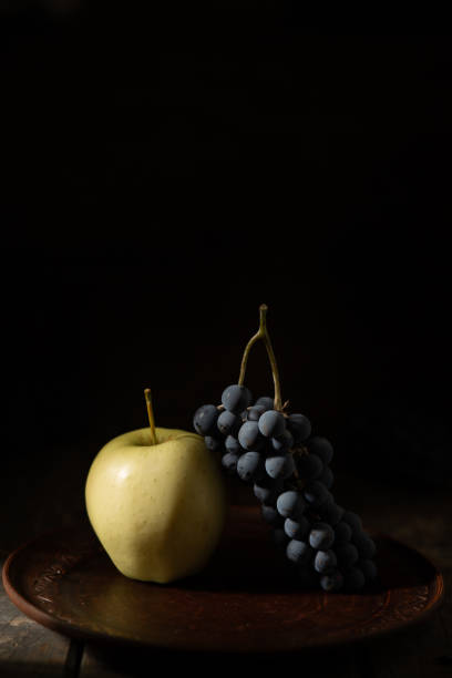 Blue grapes and green apple on a clay plate