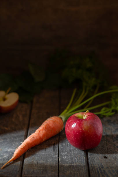 istock Red apple and fresh carrots on a wooden table 2137577958