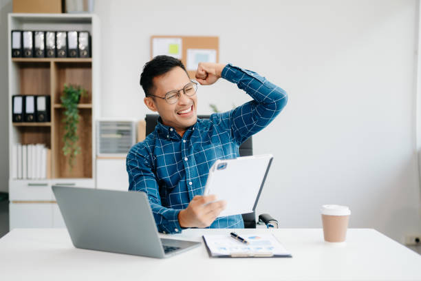 istock Young handsome man typing on tablet and laptop while sitting at the working table office 2137585278