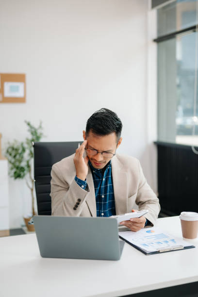 istock Young handsome man typing on tablet and laptop while sitting at the working table office 2137585284