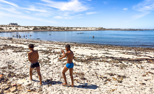 Port Nolloth, South Africa - March 16, 2024: African children playing on a beach in small coastal town
