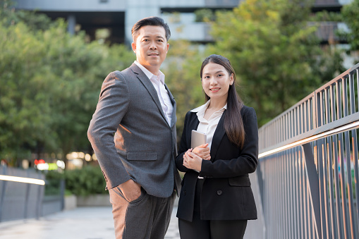 Professional man and woman standing confidently outdoors with office buildings backdrop
