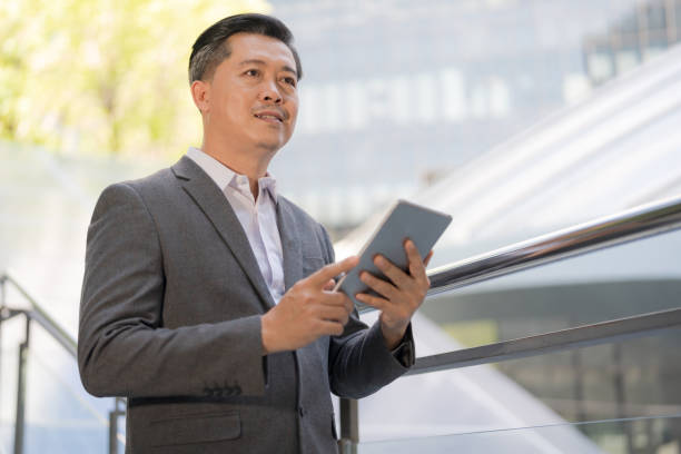 istock Confident businessman using tablet outdoors 2137610593