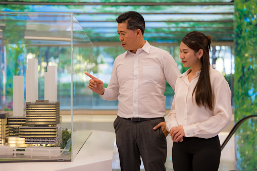 Two corporate colleagues in formal attire analyzing a building model