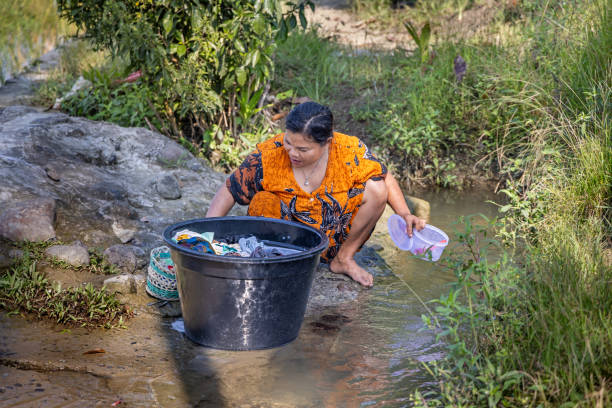Pune, India - July 30 2023: A woman washing clothes on the banks of the Indrayani river at Talegaon near Pune India.