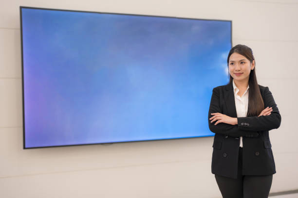 Professional woman in business attire stands before a blank presentation screen