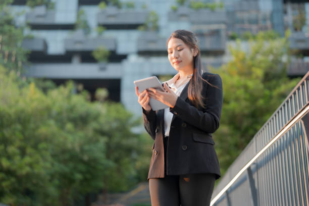 istock Professional woman works on her tablet while standing outside a modern office building 2137651583