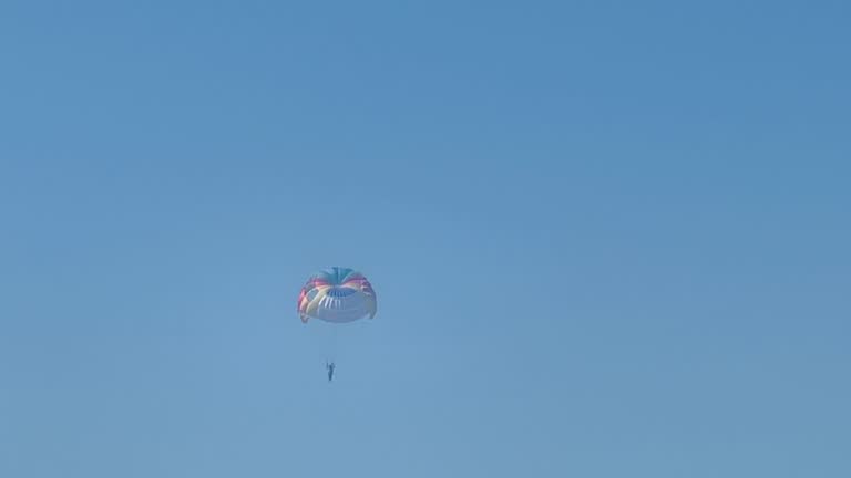Parasailing above the sea, colourful parachute soaring in clear blue sky