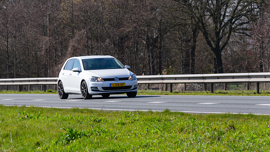 Netherlands, Overijssel, Twente, Wierden, March 19th 2023, side/front view close-up of a Dutch white 2013 Volkswagen 7th generation Golf station wagon  driving on the N36 at Wierden, the Golf has been made by German manufacturer Volkswagen since 1974, the N36 is a 36 kilometer long highway from Wierden to Ommen