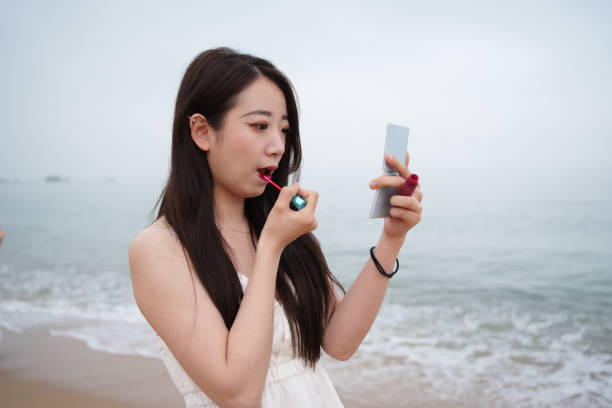Tourists applying lipstick at the beach